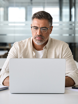 A gentleman looking at his computer in his office. 