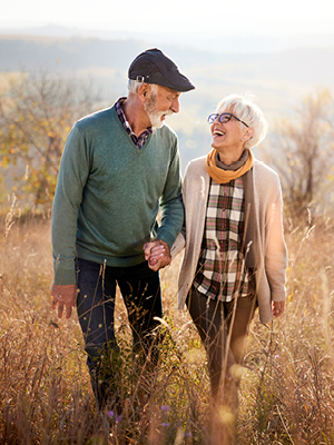 An older man and woman laughing and walking in tall grass