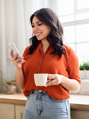 A lady drinking coffee and looking at her phone