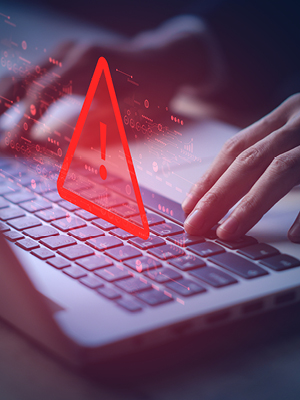 Hands typing on a laptop with a red triangle alert symbol